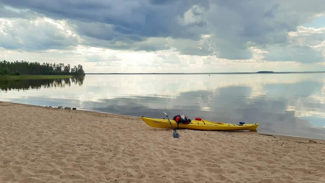 Keltainen kajakki tyynen järven rannalla.